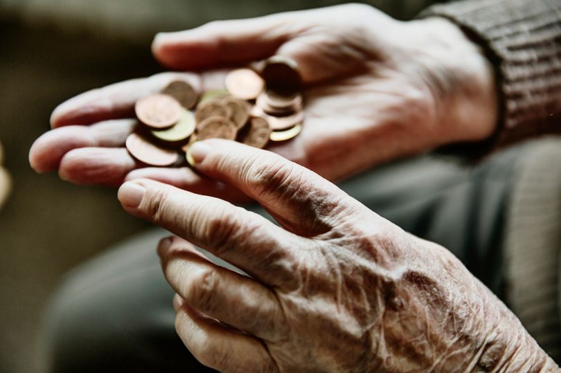 Elderly woman with her hands out with coins in it