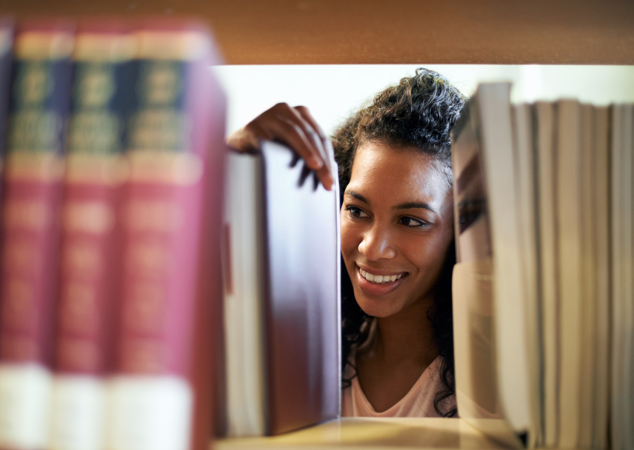 A women smiling looking at books on shelf.